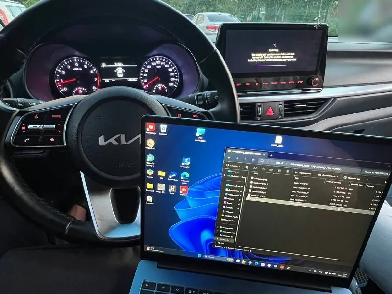 Салон Kia K3, ноутбук с файлами прошивки на фоне руля